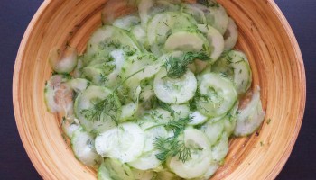 Wooden bowl with German cucumber dill salad (Gurkensalat)